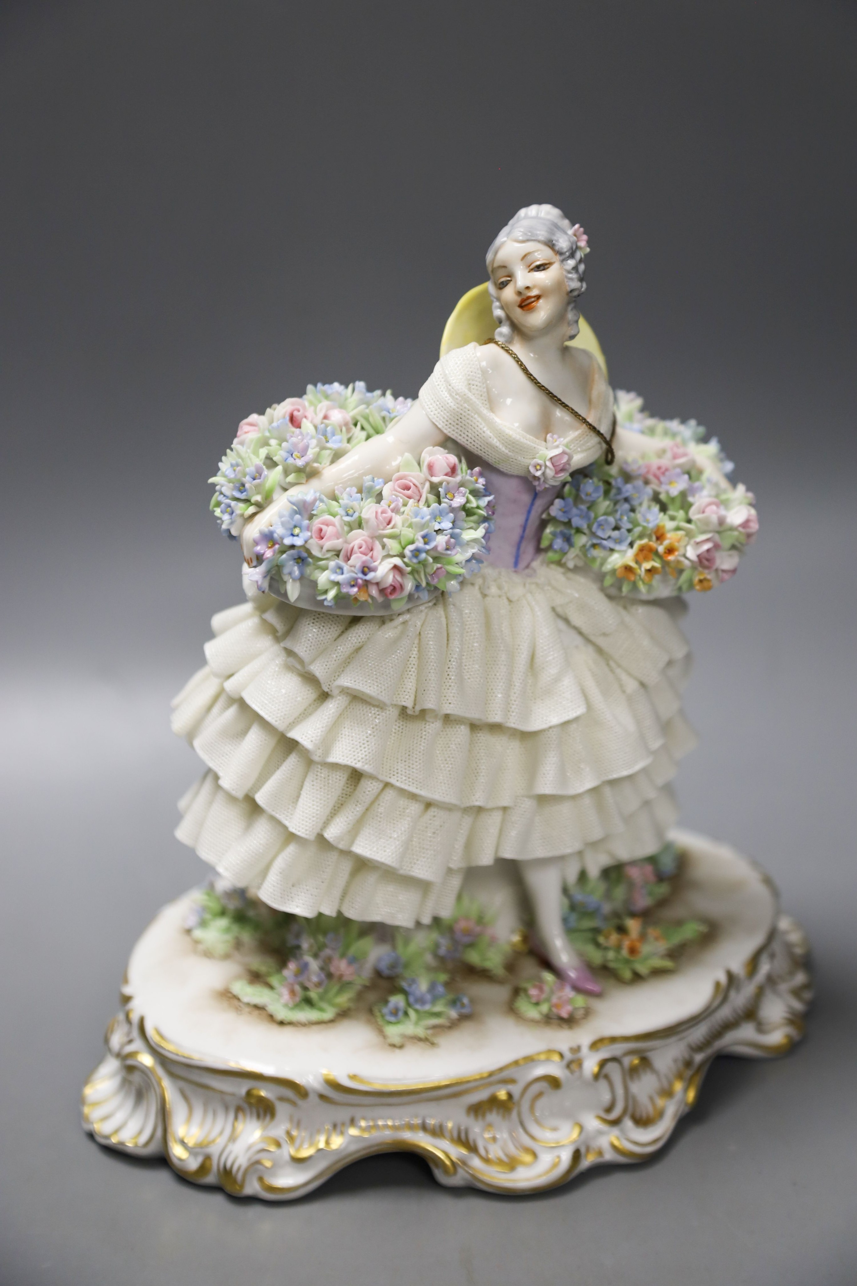 A Luigi Fabris porcelain figure of a lady wearing a crinoline dress, holding baskets of flowers, and two other figural groups (3)